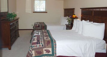 Quarto com duas camas, cômoda, mesa de cabeceira e uma janela.