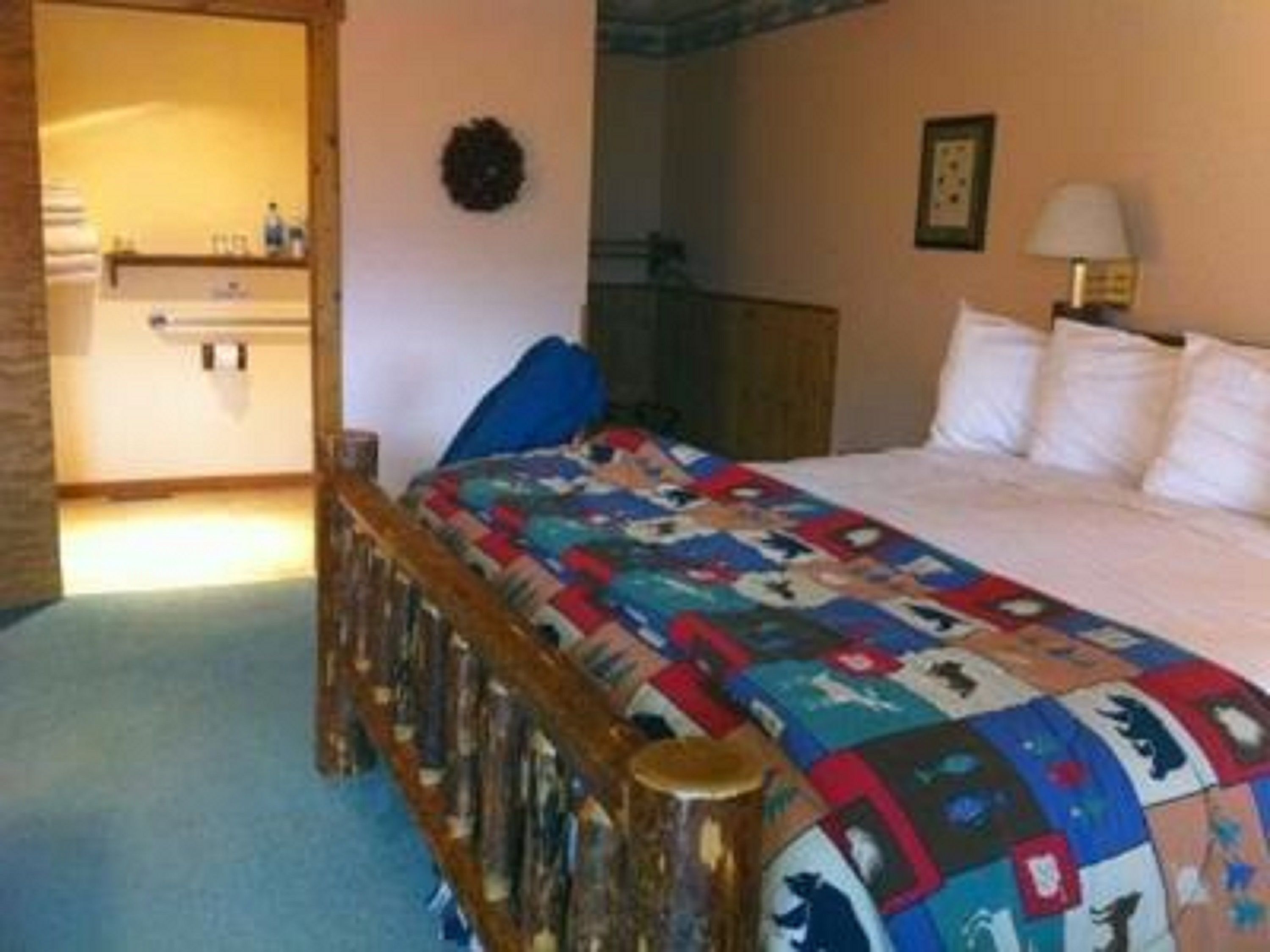 Una camera da letto con un letto a letto in legno, una coperta colorata, un comodino e una lampada.