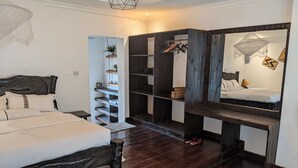 A bedroom with a bed, a wooden bench, a shelf with plants, and a wardrobe. - Inside Afrika Boutique Hotel (Kigali)