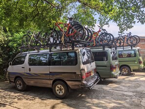 Two vans parked in a lot with bicycles mounted on racks. - Inside Afrika Boutique Hotel (Kigali)