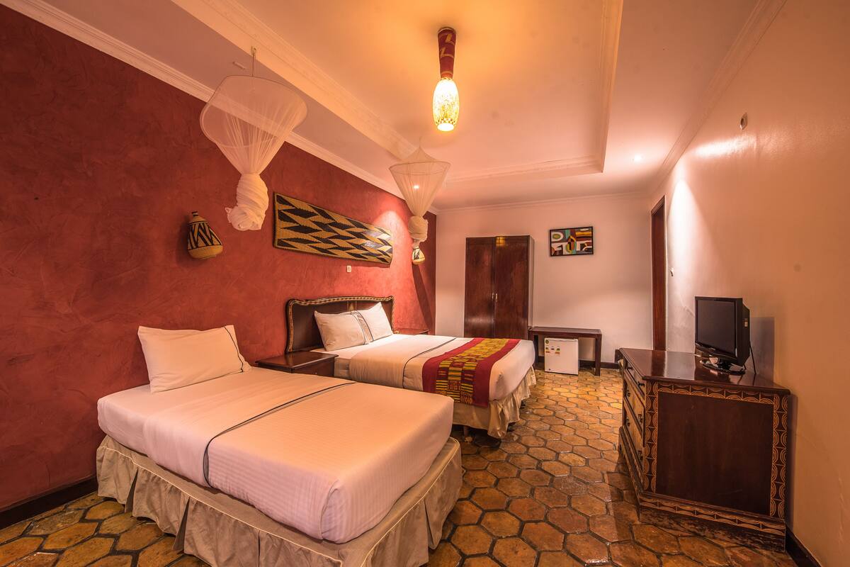 A hotel room with two beds, a television, and a small desk.