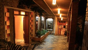 A hallway with a stone floor, wooden shelves, and hanging lights. - Inside Afrika Boutique Hotel (Kigali)