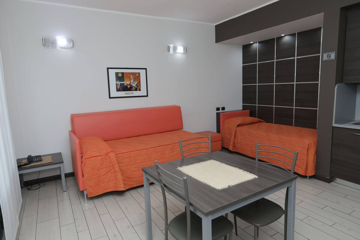 A compact living space with a sofa, a dining table, and a kitchenette area.