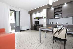 A modern kitchen with a dining area, a TV, and a microwave. - Hotel Residence Aurora (Paderno Dugnano)