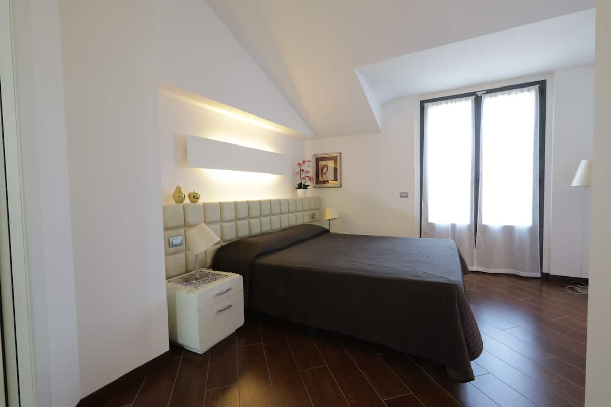 A bedroom with a bed, nightstand, and a window with curtains.