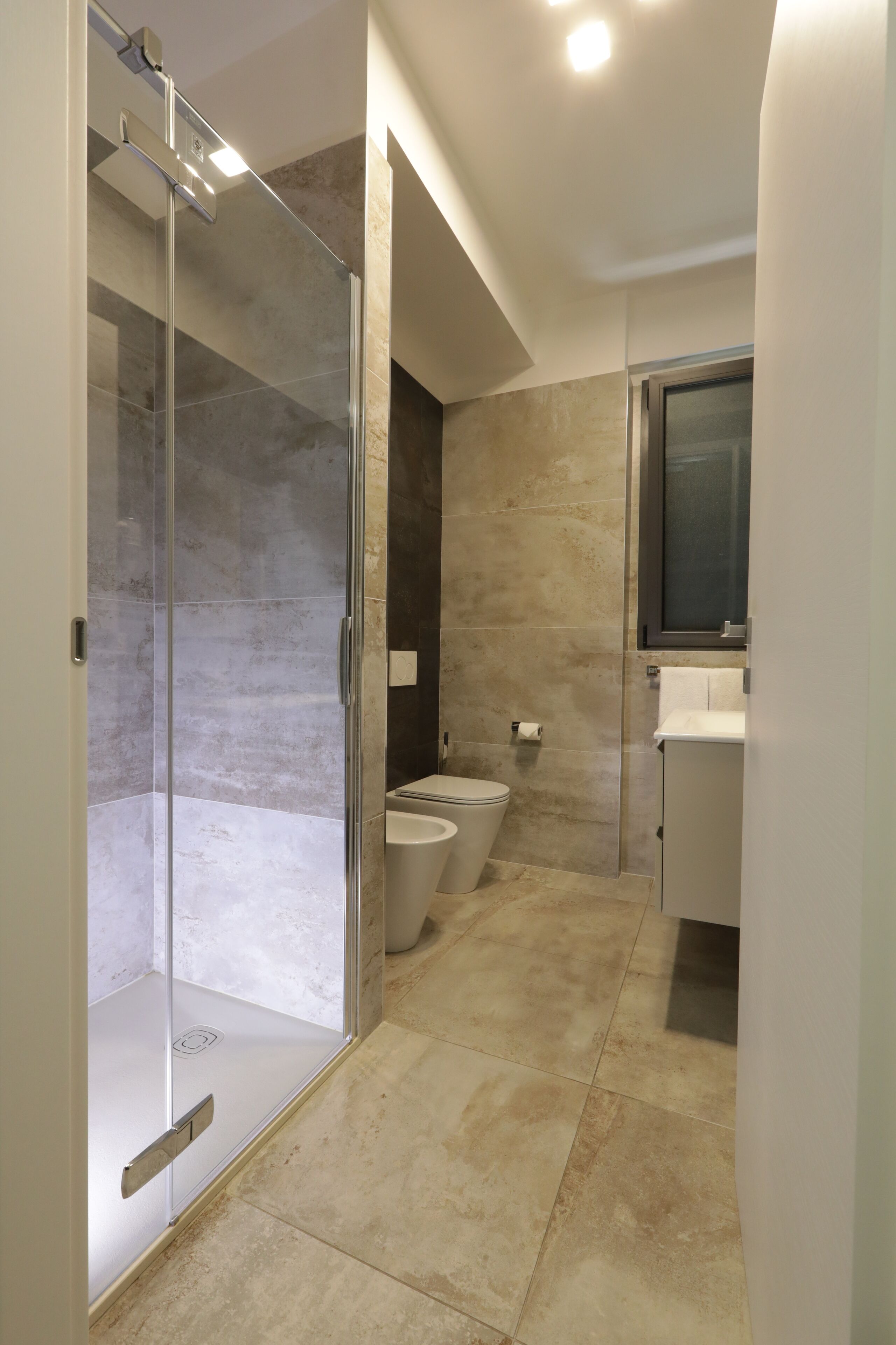 Un baño moderno con ducha de vidrio, inodoro y lavabo.