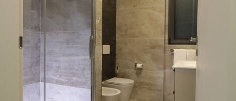 Un baño moderno con ducha de vidrio, inodoro y lavabo.