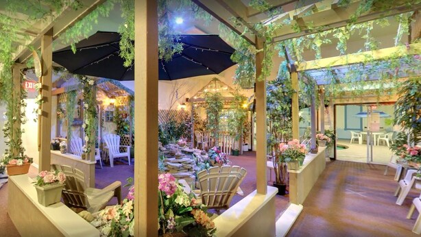 An indoor garden with wooden pergolas, seating areas, and potted plants. - Colonial Resort-1000 Islands (Gananoque)