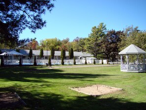 A gazebo, a swimming pool, and a building with a fenced patio area. - Colonial Resort-1000 Islands (Gananoque)