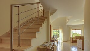 Um interior moderno com escada de madeira, área de jantar e sala de estar com sofá.