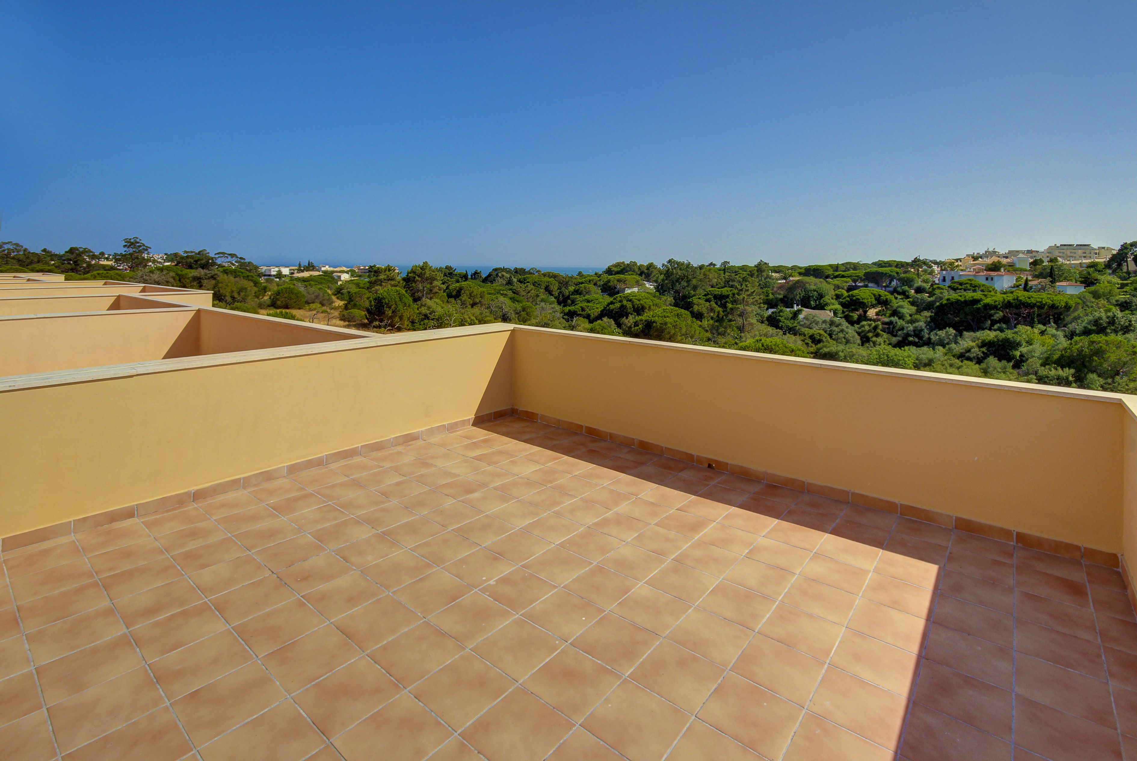 A rooftop terrace with a tiled floor and a view of a coastal landscape.