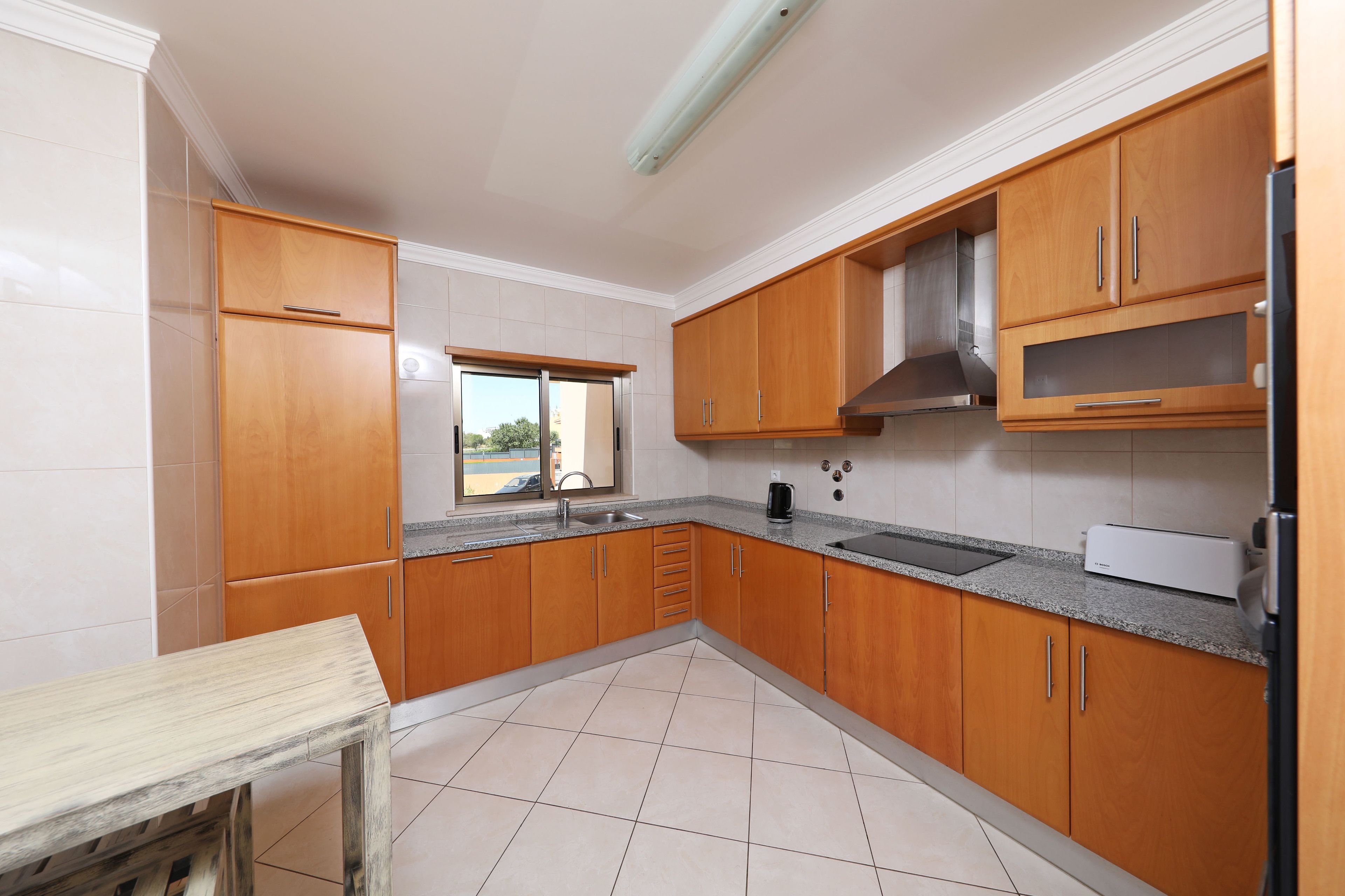 Une cuisine avec des meubles de rangement en bois, un plan de travail et une fenêtre.