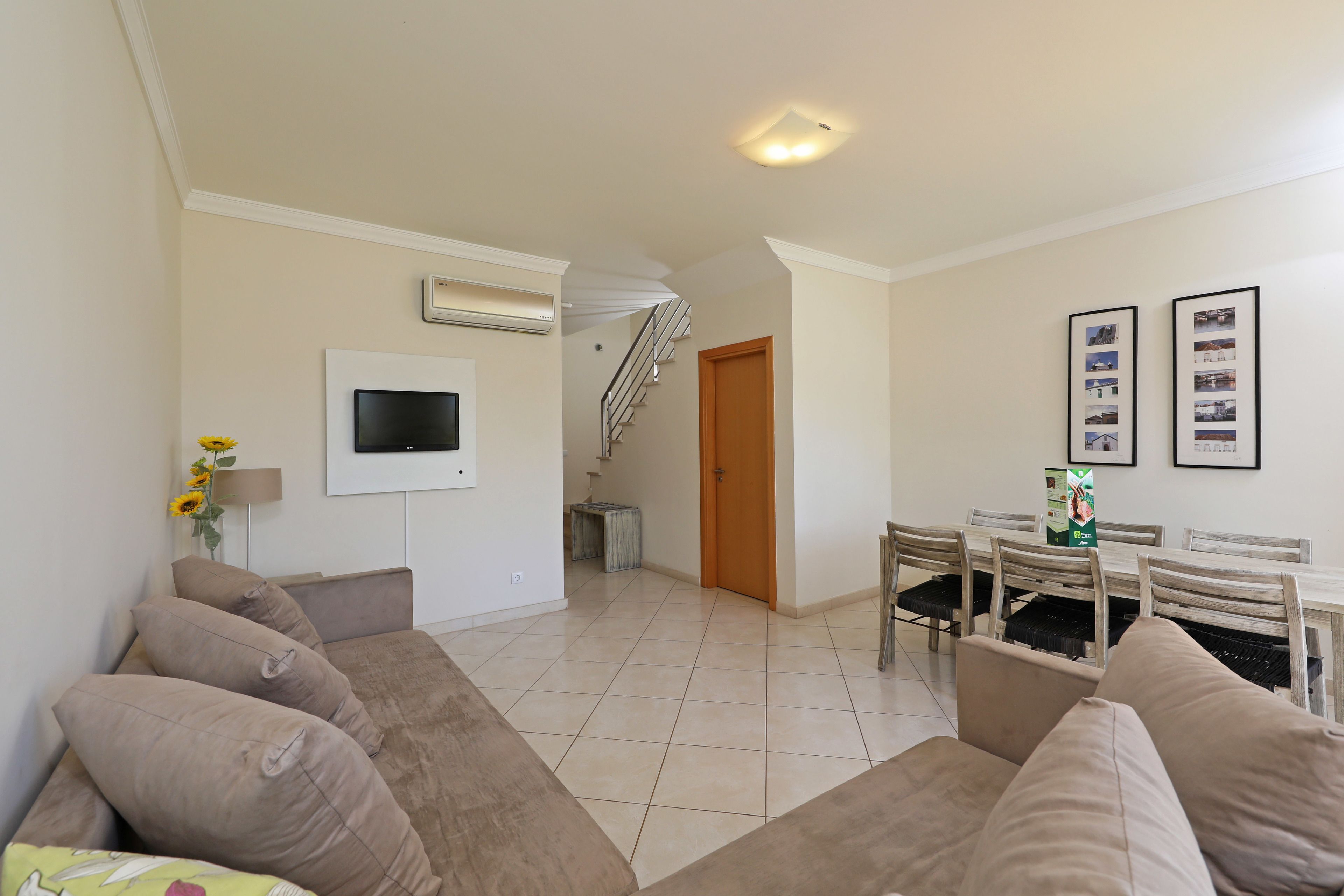 A living room with a sofa, TV, and dining area with chairs and a table.