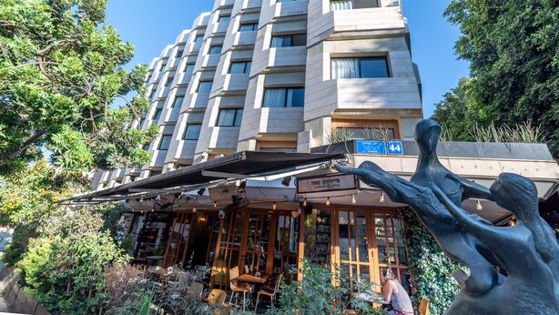 A multi-story hotel with outdoor seating and a large tree sculpture. - 130 Rock Apartments (Tel Aviv)