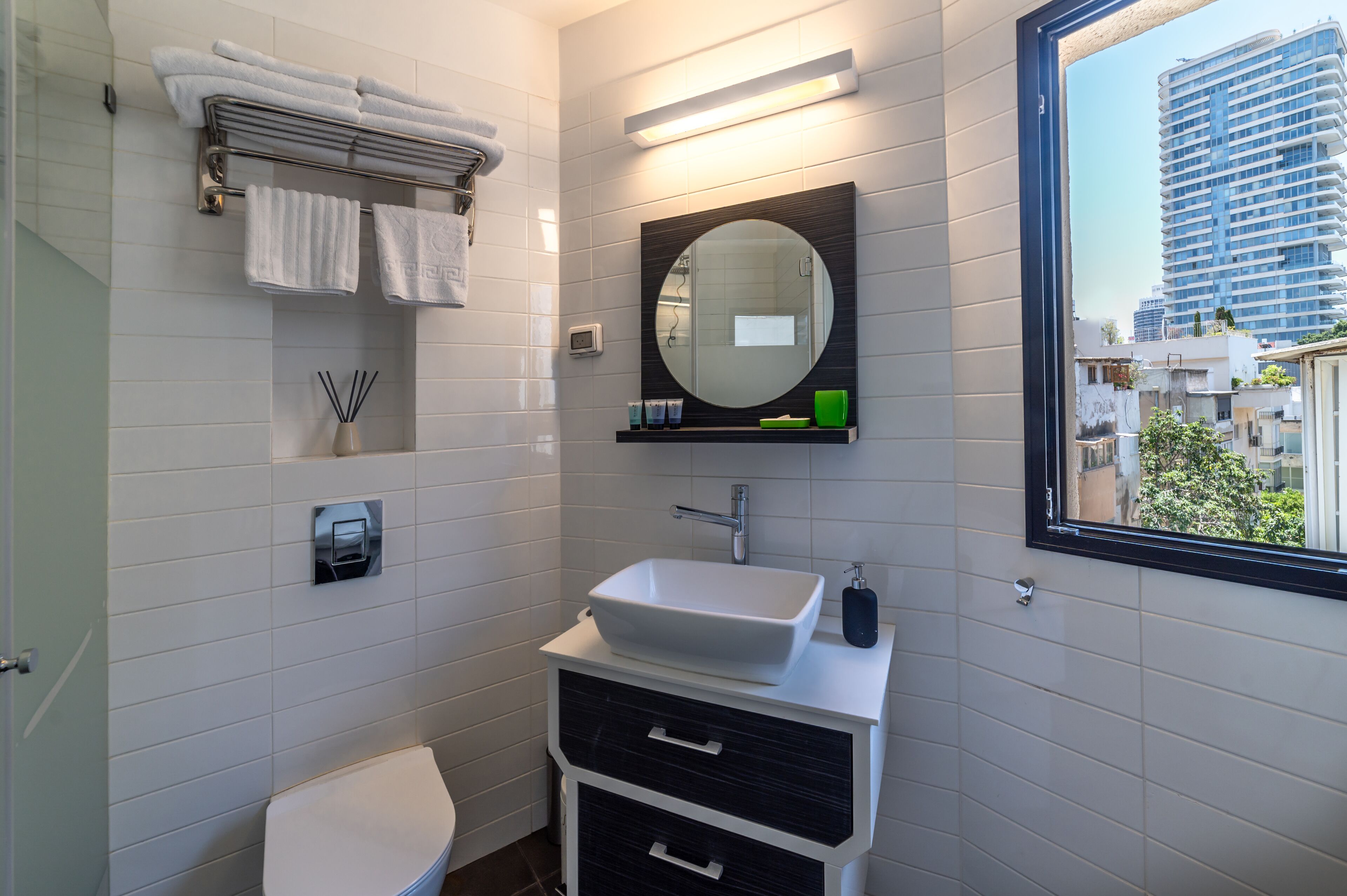 A modern bathroom with a white sink, black vanity, and a large mirror.