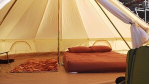 A tent with a bed, pillows, a blanket, and a small table with items. - Phu Mok Dok Mai Resort (Wiang Kaen)