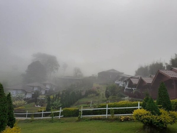 A foggy village with traditional houses and a white fence.