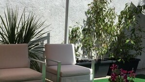 A seating area with two chairs and a table, surrounded by potted plants. - WW Hostel & Suites (Coimbra)