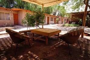 Relax in a tranquil outdoor space with a wooden table and woven chairs, shaded by a large umbrella.