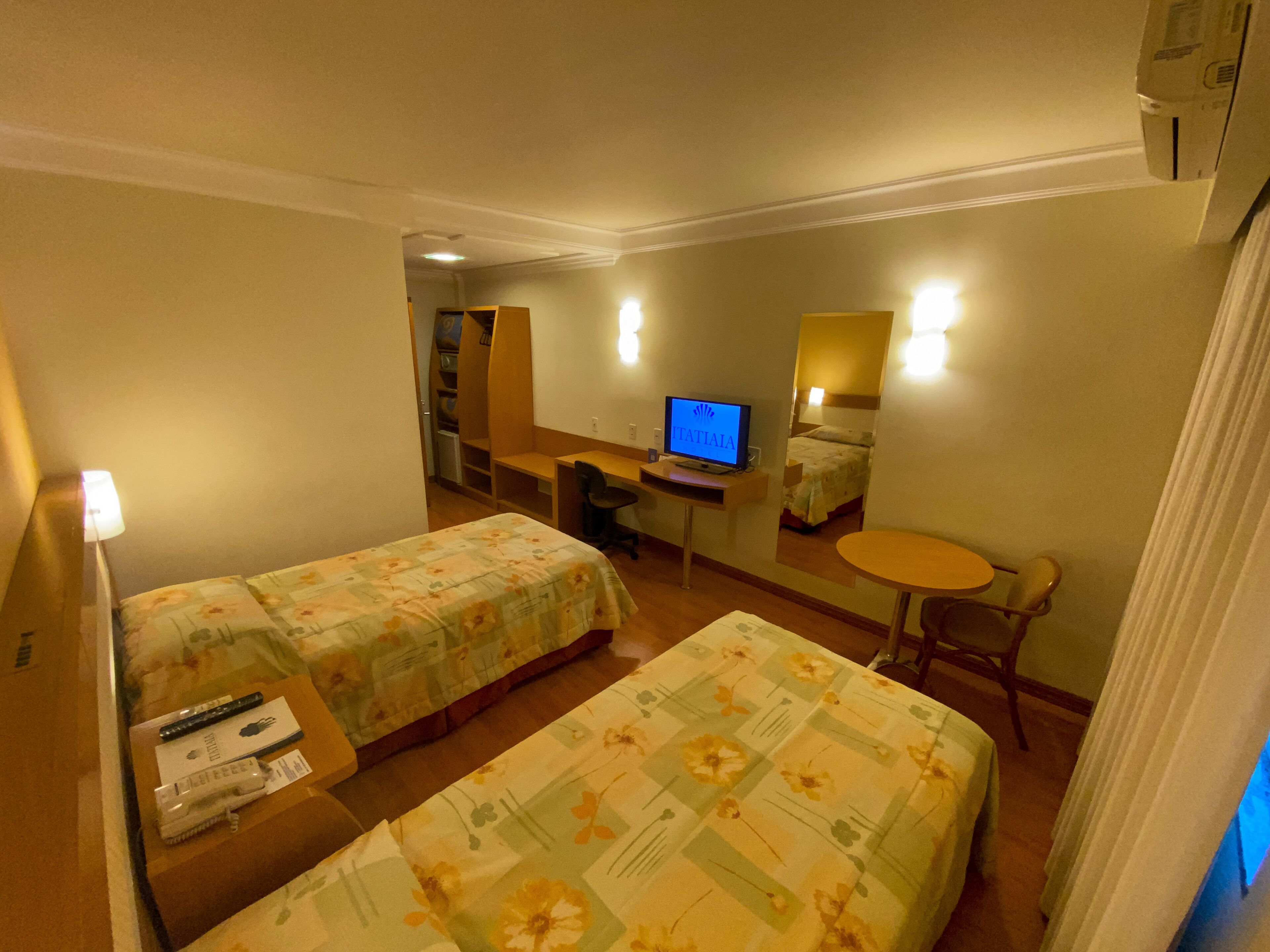 Una habitación de hotel con dos camas, un escritorio con ordenador, una mesita pequeña y una silla.