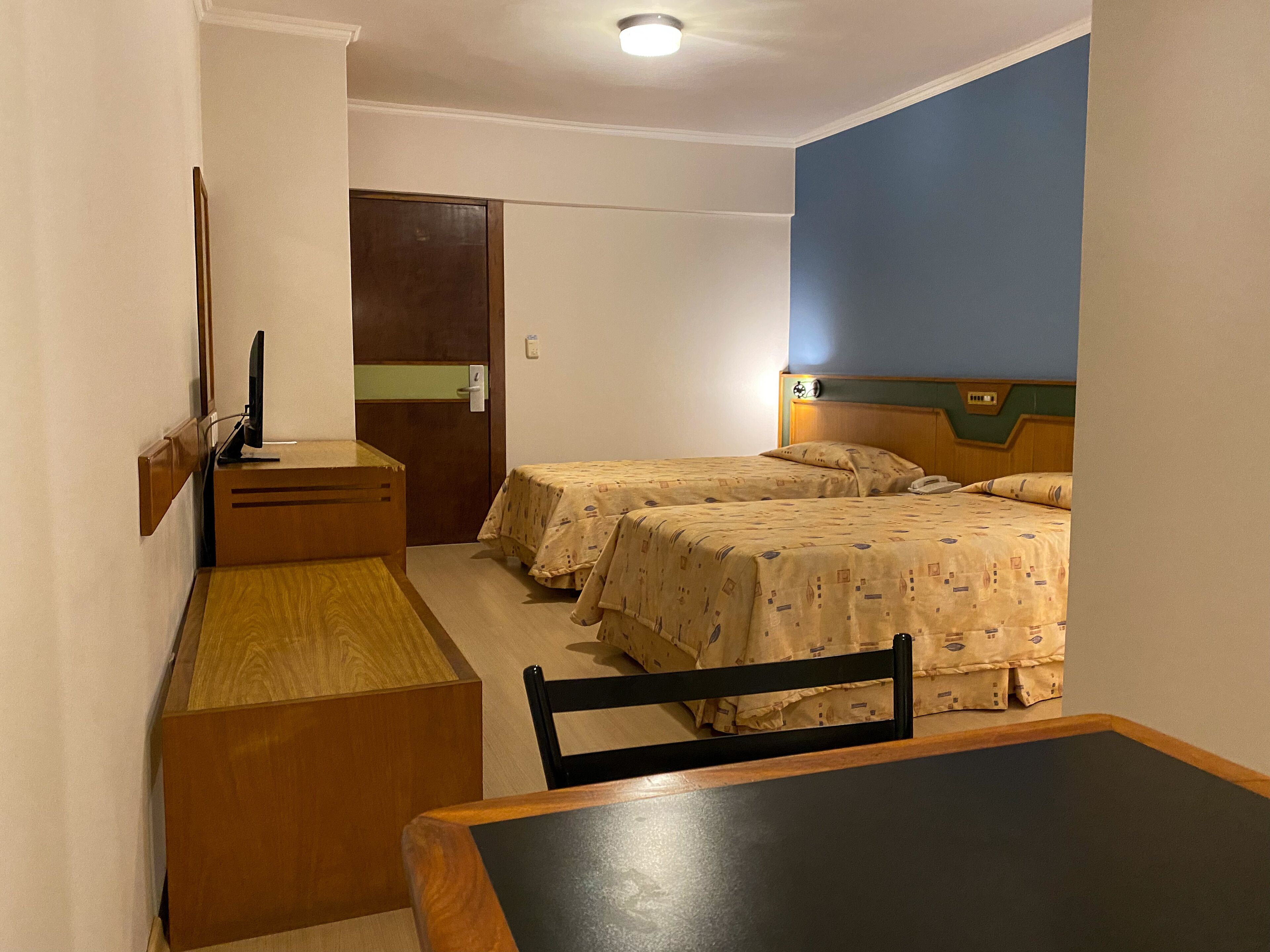 Una habitación pequeña y limpia con dos camas, un escritorio y una silla.