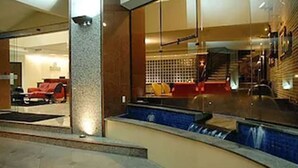 Un vestíbulo de hotel con mostrador de recepción, zona de estar y piscina.