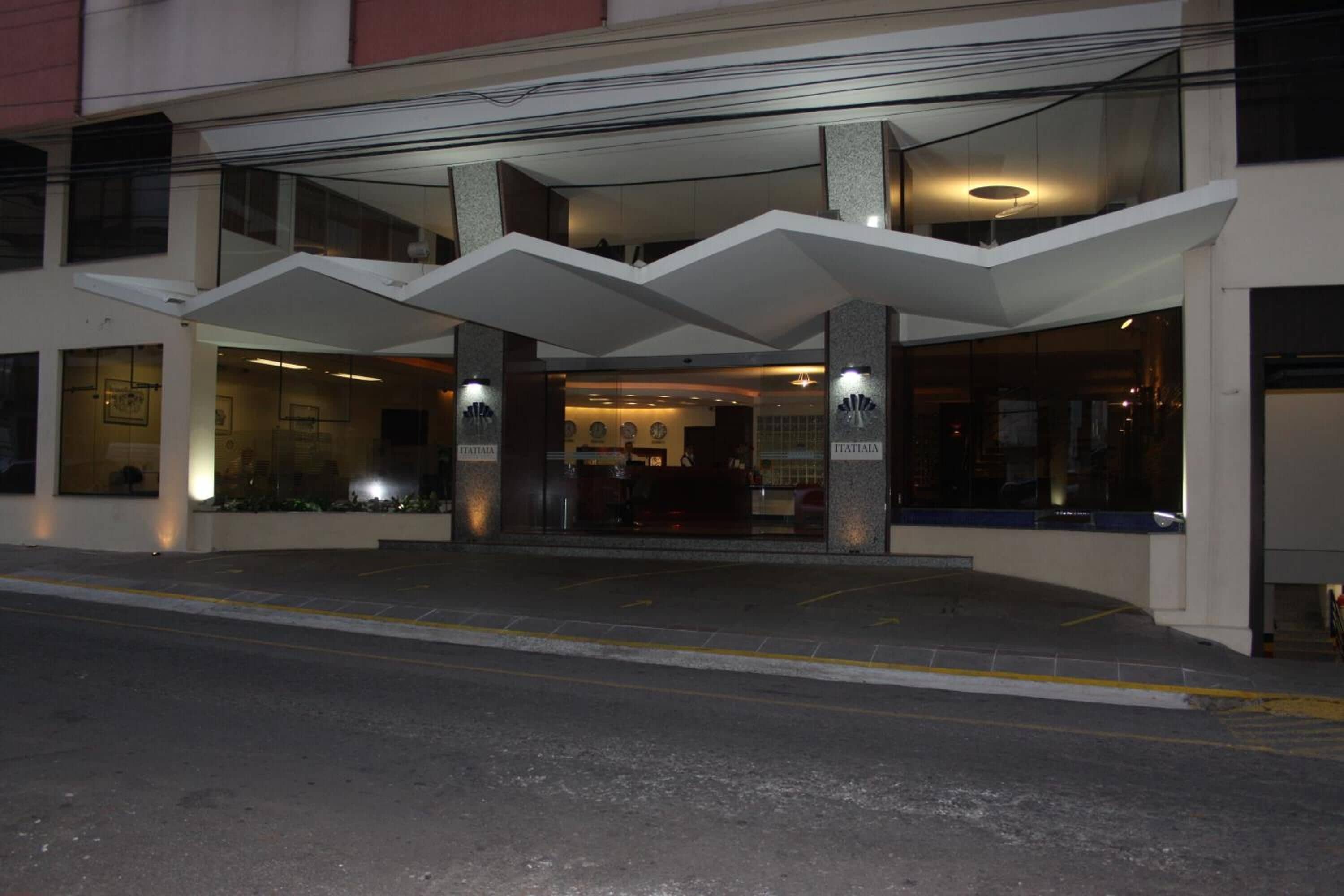 A hotel entrance with a modern design, featuring a glass facade and a prominent overhang.