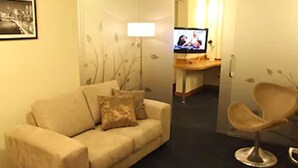 Una sala de estar con un sofá, una silla, un televisor y un escritorio.