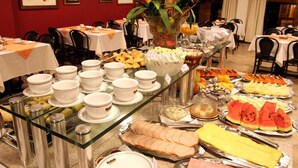 Un bufé con diferentes opciones de comida y un expositor de vidrio con cuencos y tazas.