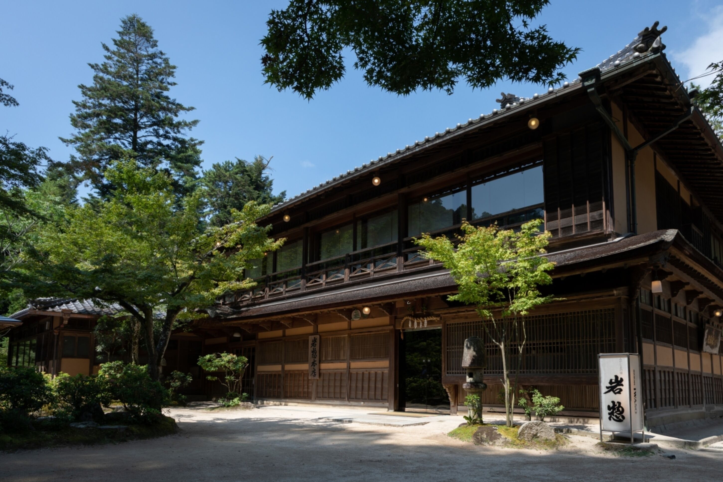 A traditional Japanese building with a wooden structure, large windows, and a stone lantern.