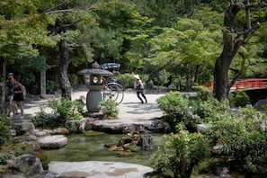 A traditional Japanese garden with a stone lantern, a small pond, and a red bridge.