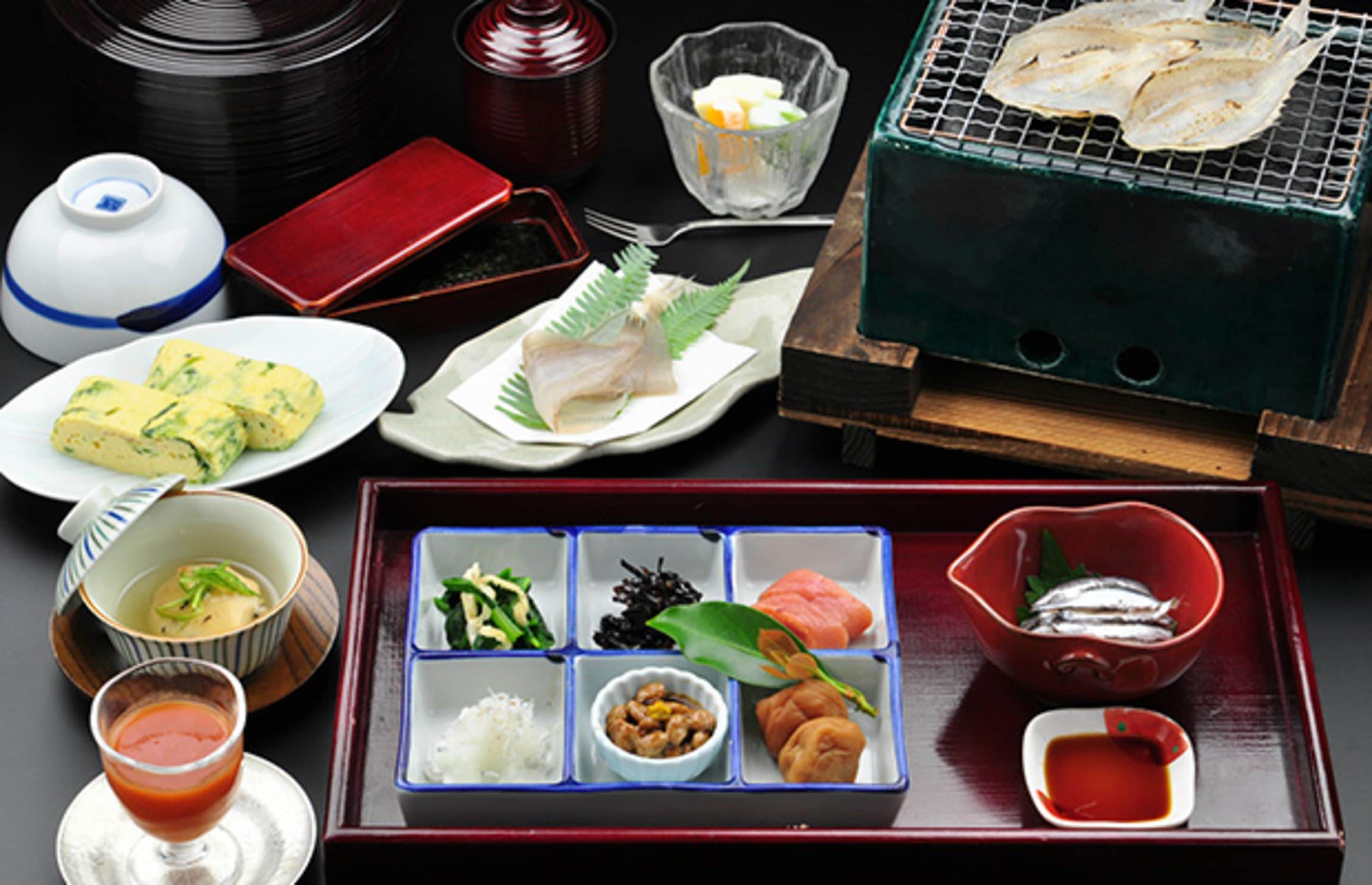 Una variedad de platos japoneses, como sushi, sashimi y tempura, sobre una bandeja.