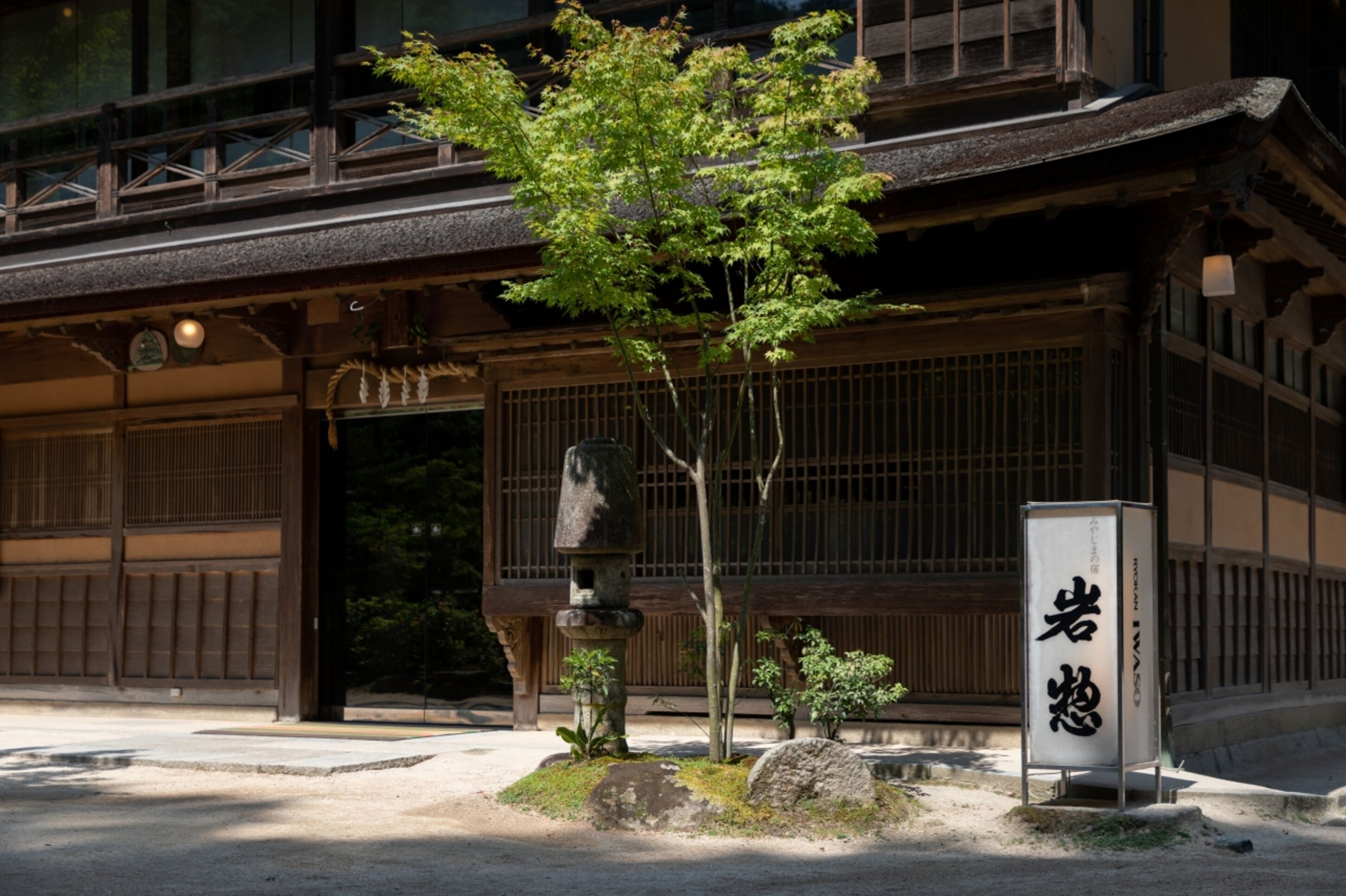Ein traditionelles japanisches Gebäude mit einer Holzfassade, einem Steinglaternen und einem Schild mit japanischen Schriftzeichen.