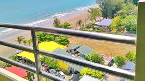 A coastal view from a balcony overlooking a beach with a few buildings and parked cars. - Blue Wave Hotel Hua Hin (Hua Hin)