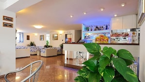 A hotel lobby with a reception desk, seating area, and a bar. - Hotel Samoa (Rimini)