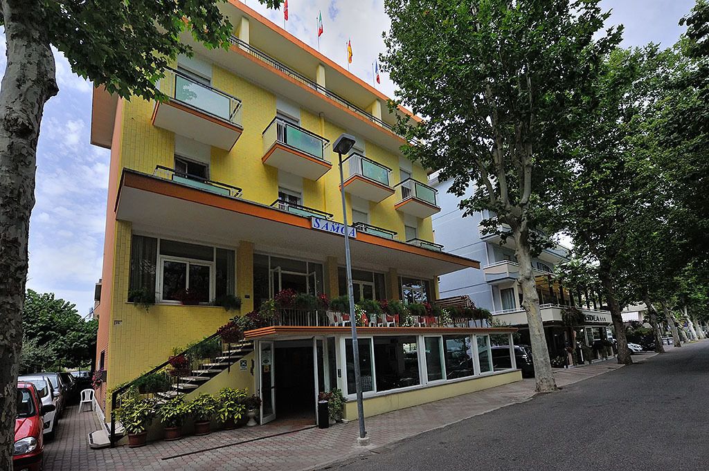 A yellow building with "SAMOA" on the facade, a staircase, and a covered entrance area.