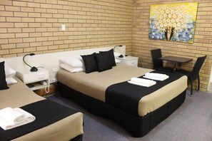 A hotel room with two beds, a desk, and a chair.
