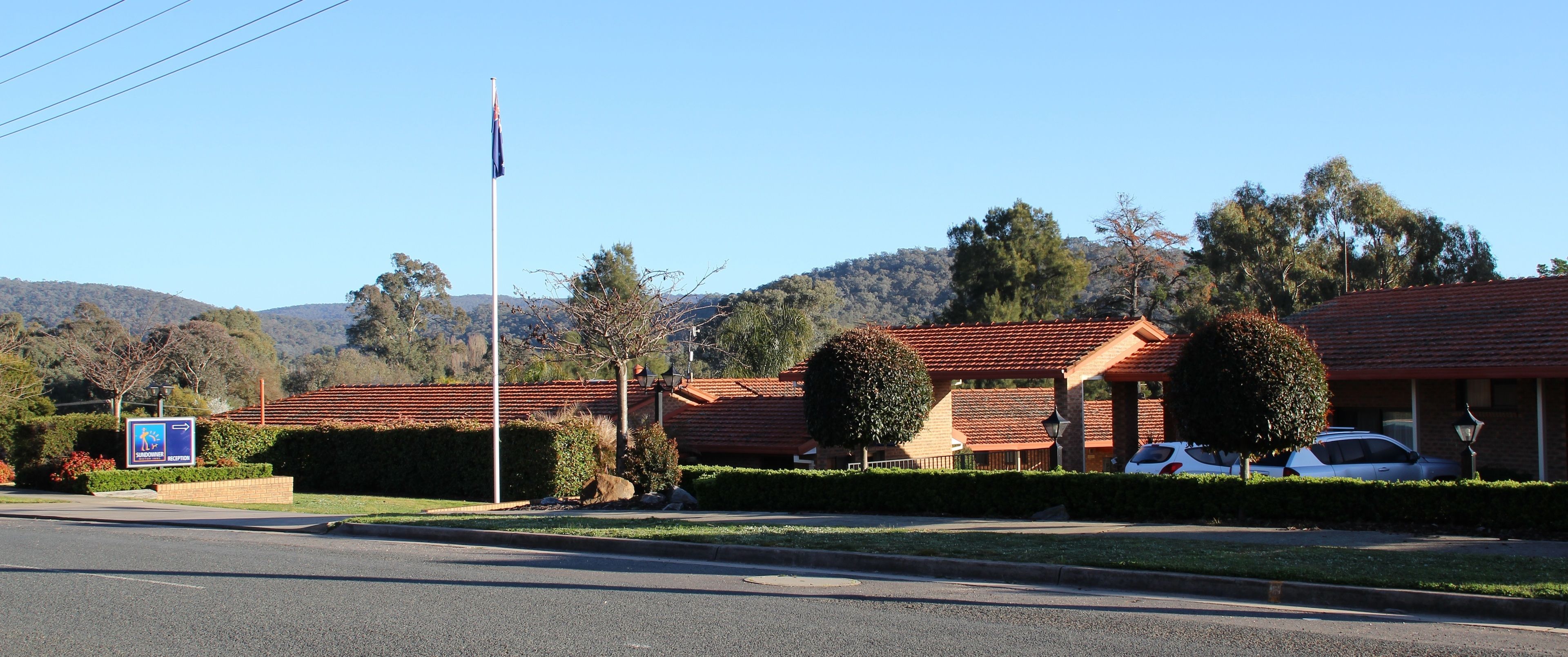 A hotel with a red-tiled roof, a flagpole, and a sign indicating a sundowner reception area.