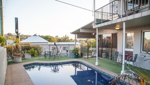 A swimming pool with a tiled deck, surrounded by potted plants and outdoor furniture. - Murwillumbah Motor Inn (Murwillumbah)