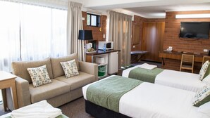 A hotel room with two beds, a sofa, a desk with a computer, a TV, and a window with curtains. - Murwillumbah Motor Inn (Murwillumbah)