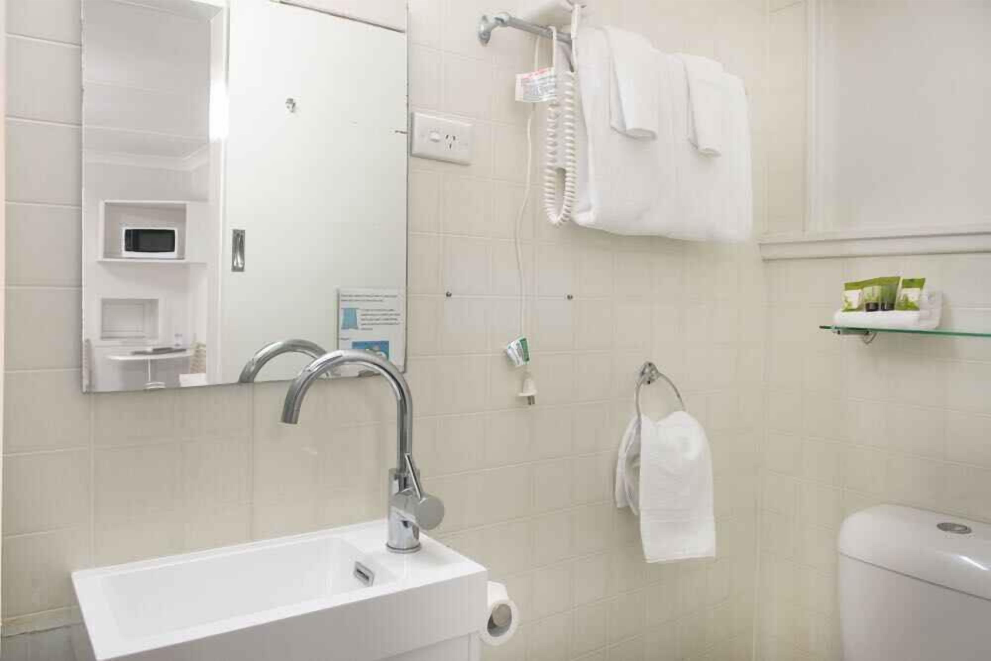 A modern bathroom with a white sink, a mirror, a towel rack, and a toilet.