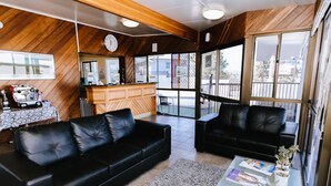 A modern living room with a black leather sofa, a coffee table with magazines, and a wooden ceiling. - Murwillumbah Motor Inn (Murwillumbah)