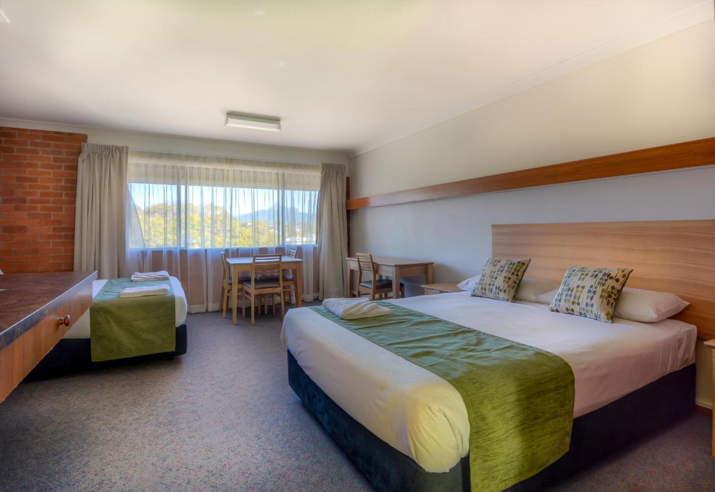 A hotel room with two beds, a desk, and a chair.