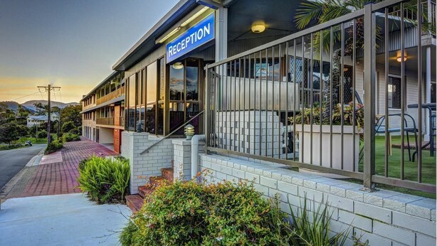 A modern reception area with a sign, glass doors, and a pathway leading to the entrance. - Murwillumbah Motor Inn (Murwillumbah)