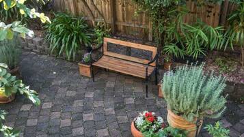 Een houten bank in een tuin met potplanten en een houten hek op de achtergrond.