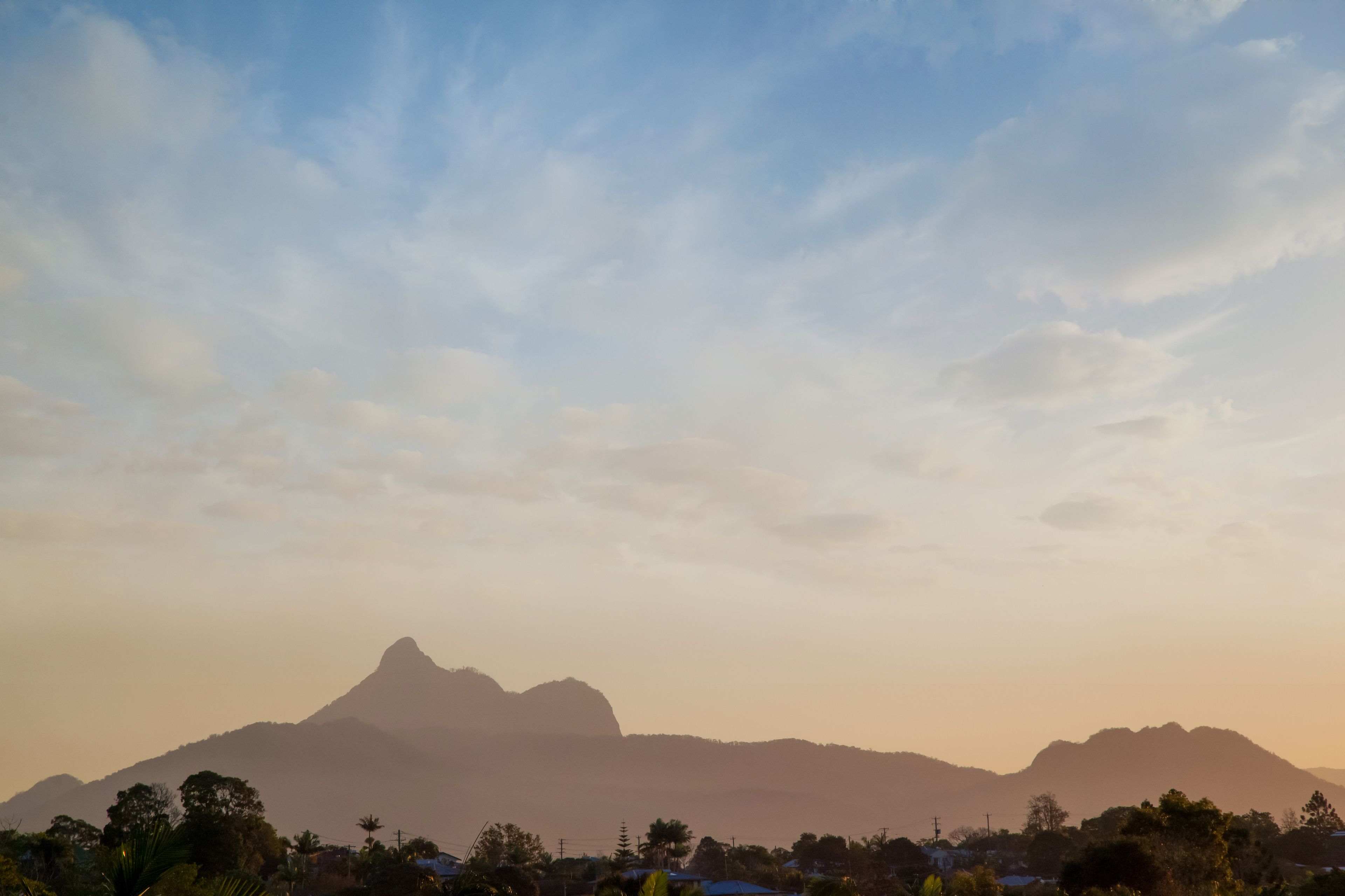 A mountain range with a prominent peak, surrounded by vegetation and buildings.