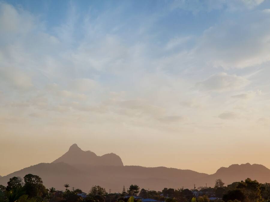A mountain range with a prominent peak, surrounded by vegetation and buildings.