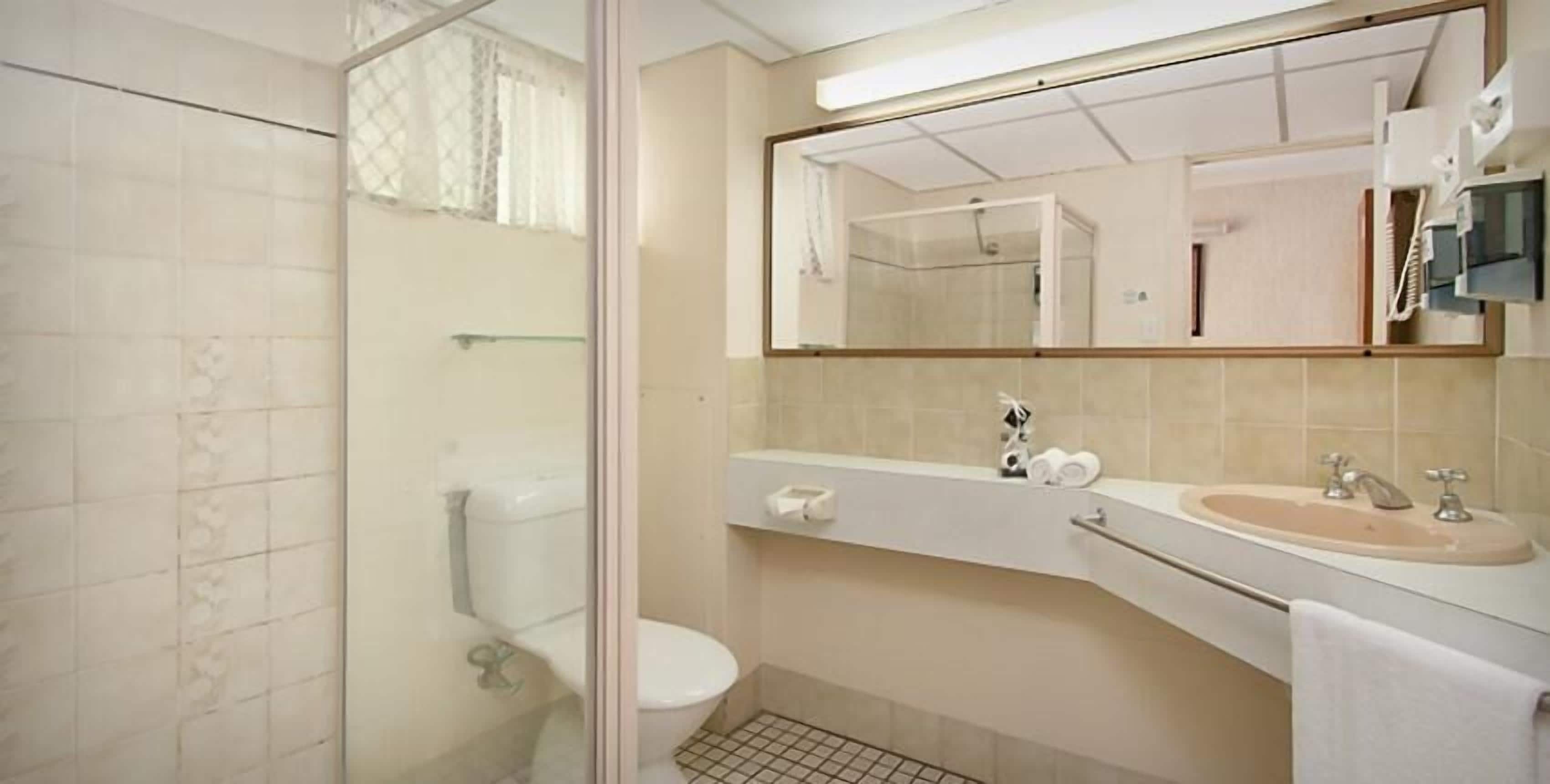 A bathroom with a toilet, sink, and mirror.