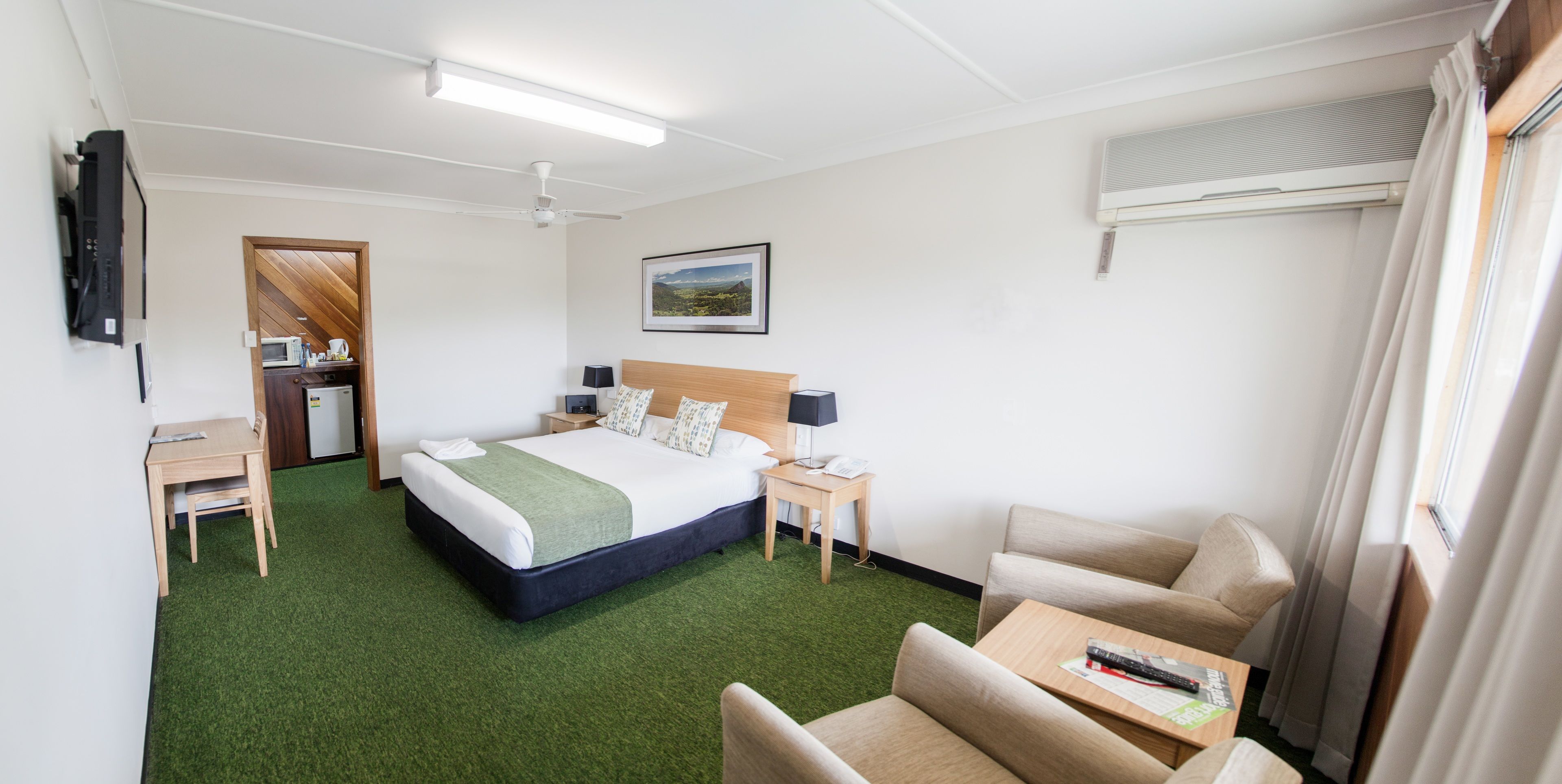 Une chambre d’hôtel avec un lit, un bureau, une chaise, une télévision et un tableau au mur.