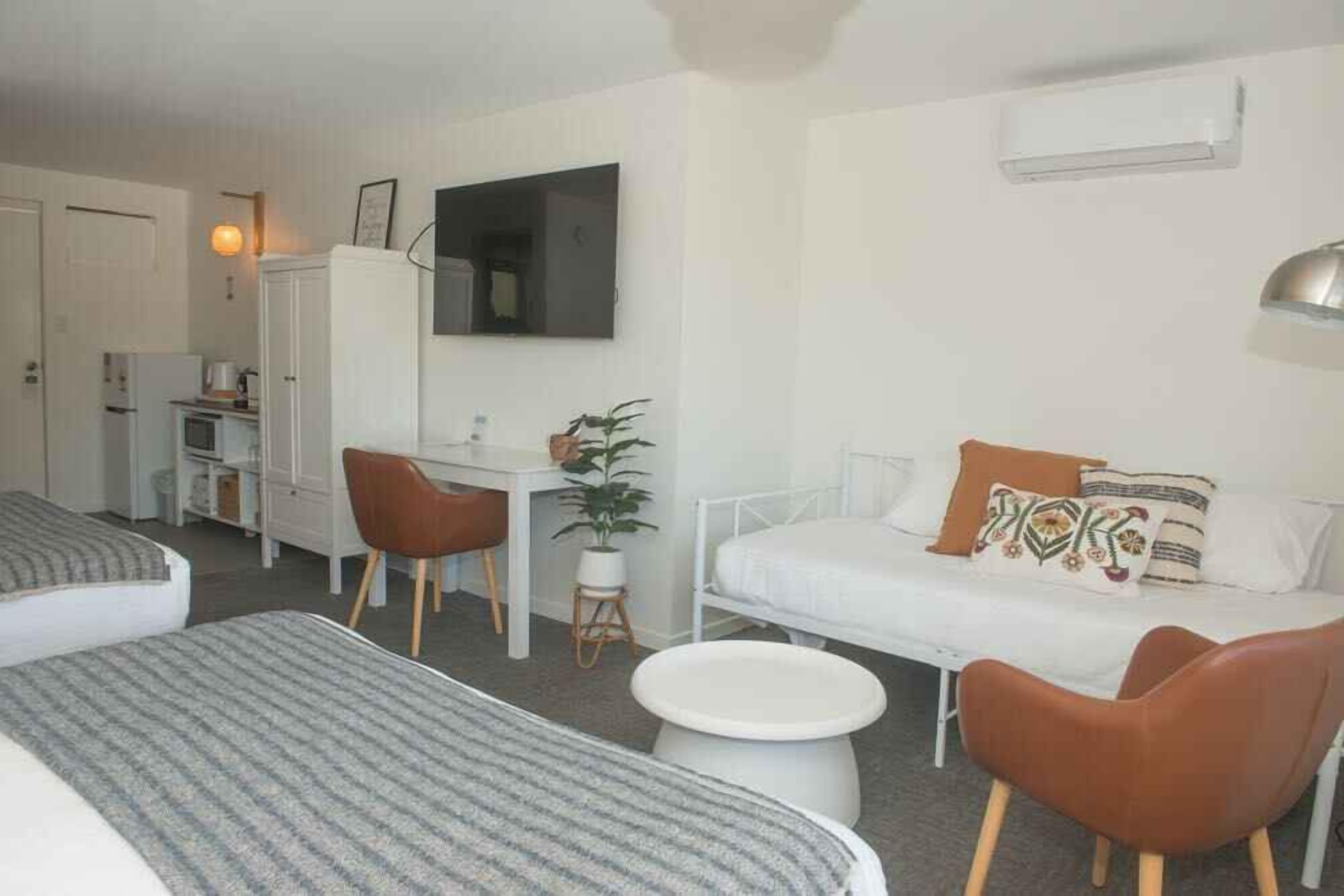 Una habitación de hotel con dos camas, un escritorio, una silla, un sofá y una mesita.